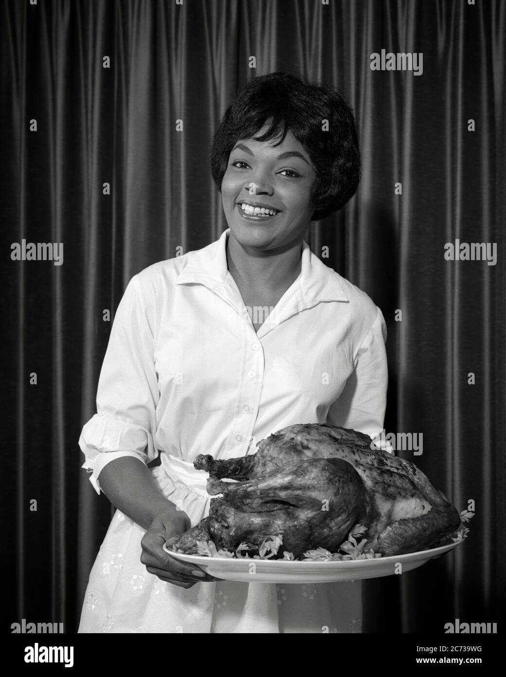 1960s SMILING AFRICAN-AMERICAN WOMAN HOLDING PLATTER WITH HOLIDAY TURKEY - n1839 HAR001 HARS HOME LIFE COPY SPACE HALF-LENGTH LADIES PERSONS INSPIRATION CONFIDENCE AMERICANA B&W EYE CONTACT HOMEMAKER HAPPINESS HOMEMAKERS CHEERFUL PRESENTING STRENGTH AFRICAN-AMERICANS AFRICAN-AMERICAN EXCITEMENT BLACK ETHNICITY HOSTESS PLATTER PRIDE HOUSEWIVES SMILES THANKFUL THURSDAY JOYFUL NATIONAL HOLIDAY STYLISH GRATEFUL JOYOUS MID-ADULT MID-ADULT WOMAN NOVEMBER BLACK AND WHITE FOOD PREPARATION HAR001 OLD FASHIONED AFRICAN AMERICANS Stock Photo