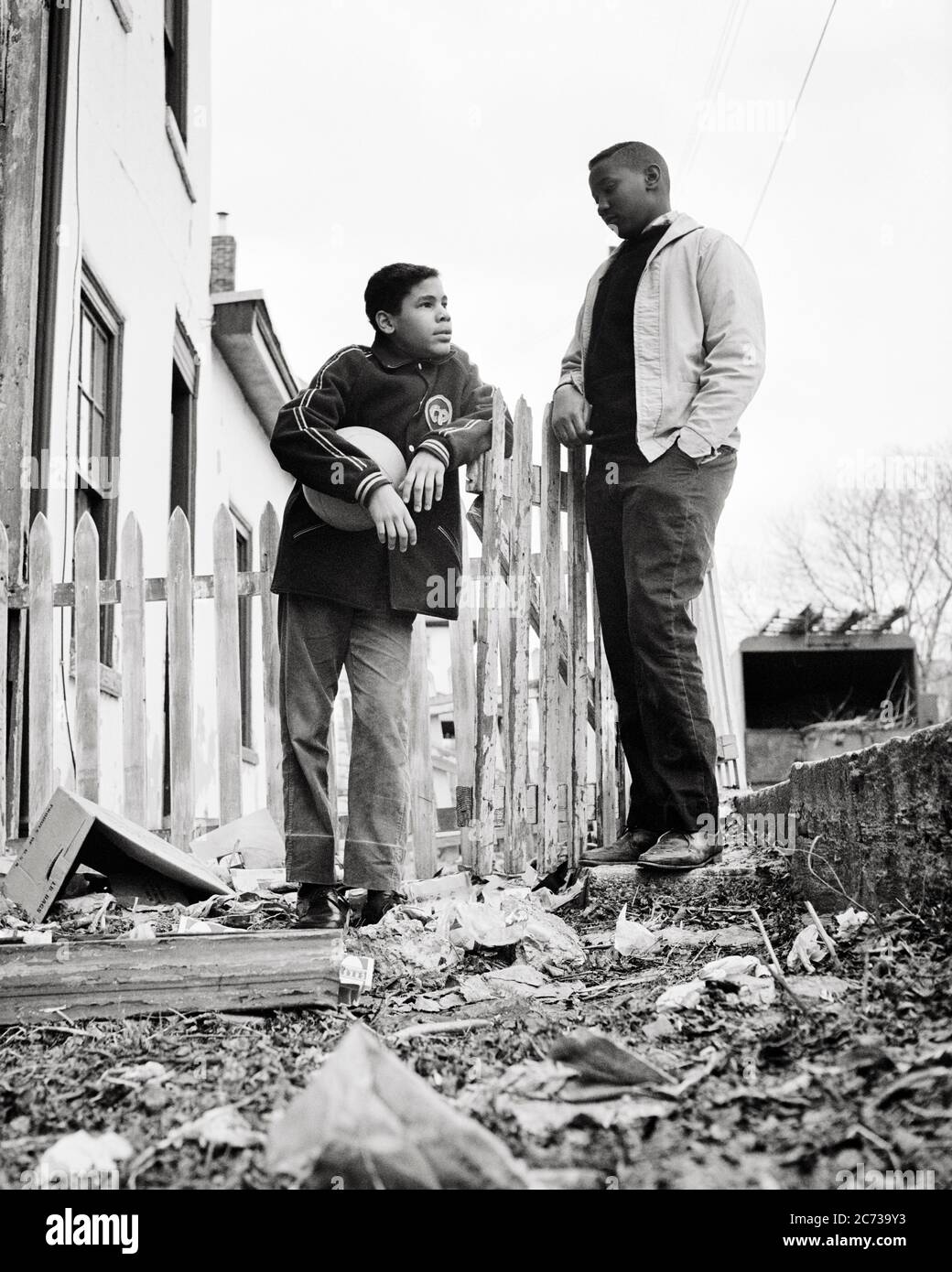 1960s TWO AFRICAN AMERICAN TEENAGE BOYS HOLDING BASKETBALL IN POVERTY STRICKEN URBAN NEIGHBORHOOD PHILADELPHIA PA USA  - n1962 HAR001 HARS JUVENILE ANGER FEAR BALANCE SAFETY COMPETITION LIFESTYLE BROTHERS POOR HEALTHINESS HOME LIFE UNITED STATES COPY SPACE FRIENDSHIP FULL-LENGTH UNITED STATES OF AMERICA MALES RISK TEENAGE BOY SIBLINGS B&W SADNESS NORTH AMERICA FREEDOM NORTH AMERICAN TEMPTATION DREAMS WELLNESS NEIGHBORHOOD STRATEGY AFRICAN-AMERICANS COURAGE AFRICAN-AMERICAN LOW ANGLE PA POWERFUL BLACK ETHNICITY PRIDE IN OF ON OPPORTUNITY SIBLING CONCEPTUAL ESCAPE DISADVANTAGED DISAFFECTED Stock Photo