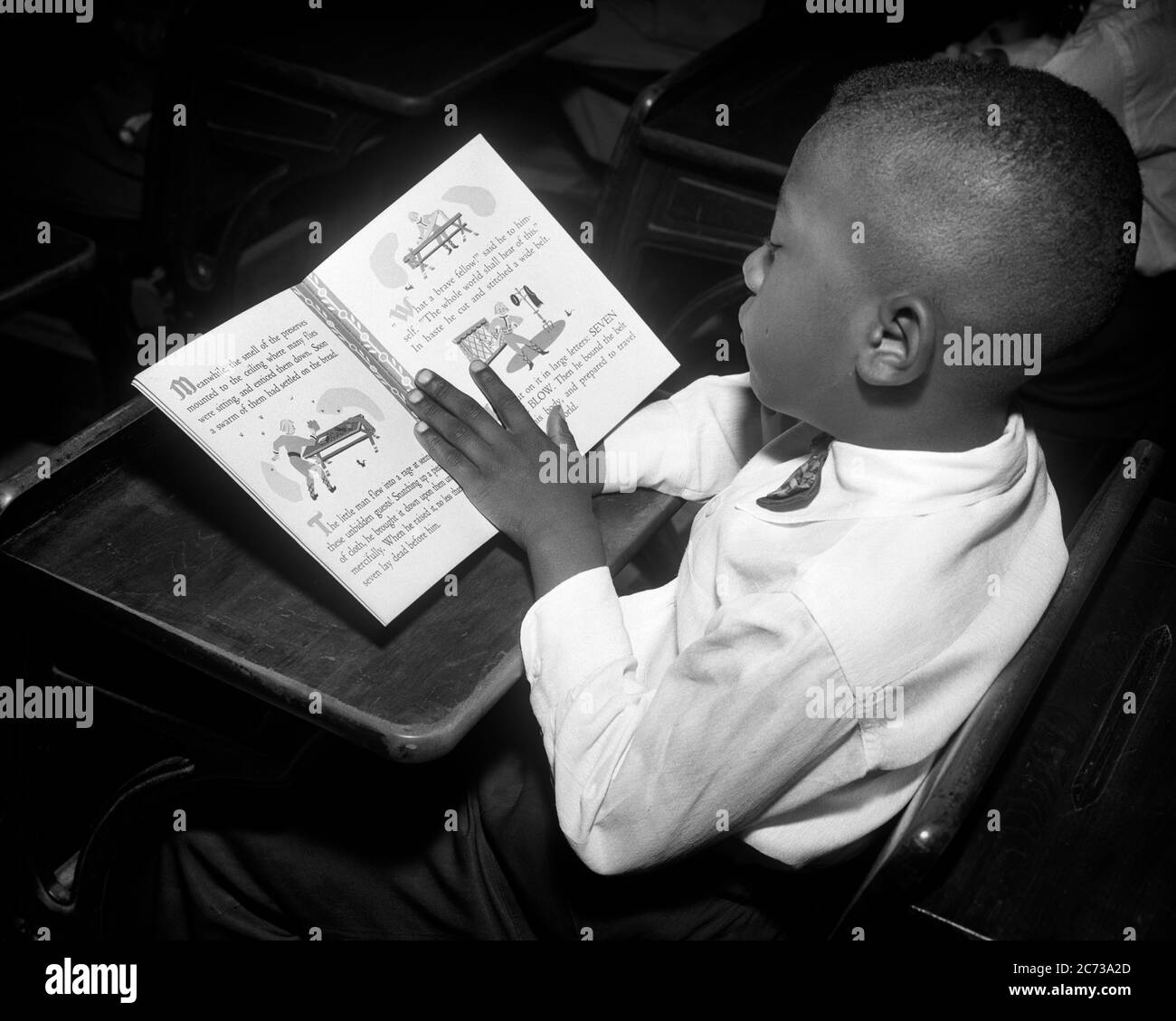 1950s ENGAGED LITERATE YOUNG AFRICAN AMERICAN BOY SITTING AT HIS PUBLIC GRADE SCHOOL DESK READING IN TEXTBOOK - n559 HAR001 HARS AFRICAN-AMERICANS AFRICAN-AMERICAN EXCITEMENT KNOWLEDGE POWERFUL PROGRESS BLACK ETHNICITY PRIDE AT IN OPPORTUNITY ENGAGED CONCEPTUAL GROWTH BLACK AND WHITE HAR001 OLD FASHIONED AFRICAN AMERICANS Stock Photo