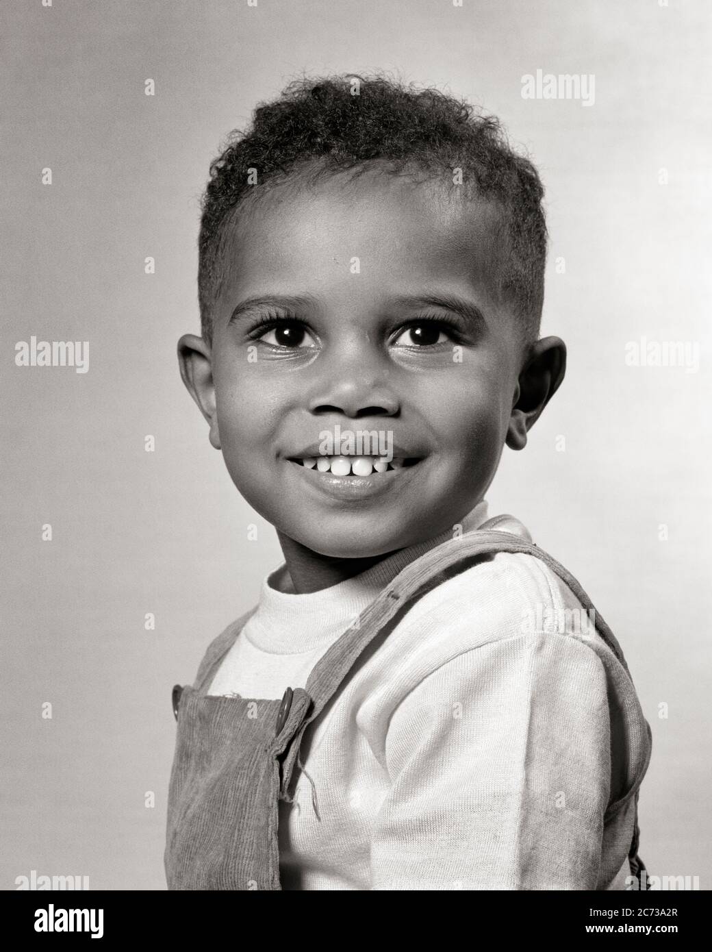 1940s 1950s PORTRAIT BRIGHT-EYED SMILING AFRICAN-AMERICAN BOY TODDLER WEARING CORDUROY BIB OVERALLS LOOKING AT CAMERA DIRECTLY  - n637 HAR001 HARS OVERALLS MALES CONFIDENCE EXPRESSIONS B&W FREEDOM DREAMS HAPPINESS WELLNESS HEAD AND SHOULDERS CHEERFUL STRENGTH AFRICAN-AMERICANS AFRICAN-AMERICAN HOPE CORDUROY EXTERIOR BLACK ETHNICITY PRIDE OPPORTUNITY SMILES DIRECTLY CONCEPTUAL IMAGINATION JOYFUL STYLISH BABY BOY PROMISE BIB GROWTH JUVENILES BLACK AND WHITE HAR001 OLD FASHIONED AFRICAN AMERICANS Stock Photo