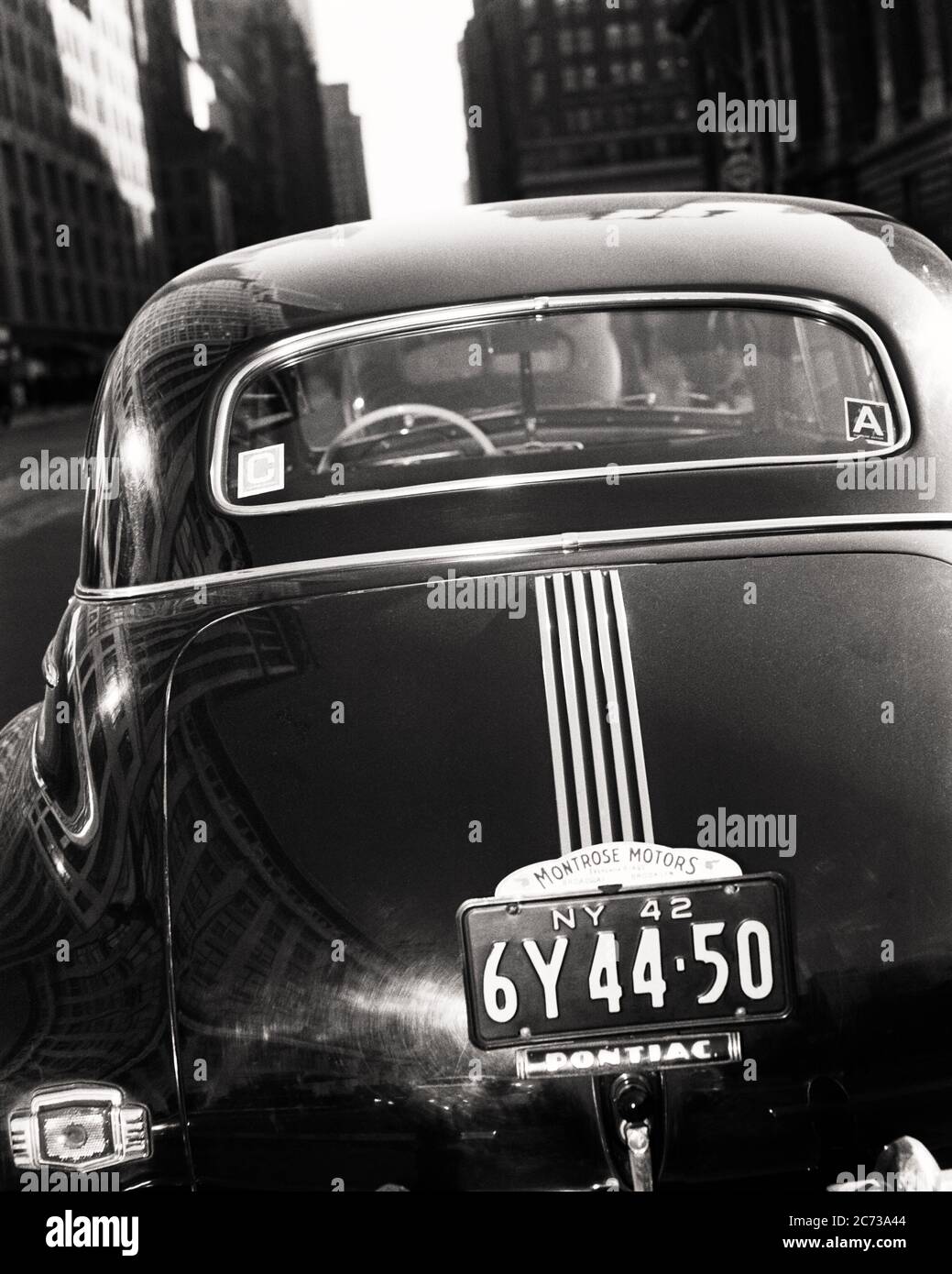 1940s REAR VIEW SHOWING GASOLINE RATION CARD DECAL STICKERS A AND C ON BACK WINDOW PONTIAC SEDAN AUTOMOBILE DURING WW2 NYC USA - q43003 CPC001 HARS AUTOS EXTERIOR LOW ANGLE WORLD WARS WORLD WAR WORLD WAR TWO WORLD WAR II A ON DISTRIBUTION NYC OCCUPATIONS GASOLINE RESOURCES NEW YORK PONTIAC RATION AUTOMOBILES CITIES RATIONING VEHICLES WINDSHIELD WORLD WAR 2 NEW YORK CITY DECALS C STICKER ARTIFICIAL BLACK AND WHITE CONTROLLED DURING OLD FASHIONED Stock Photo