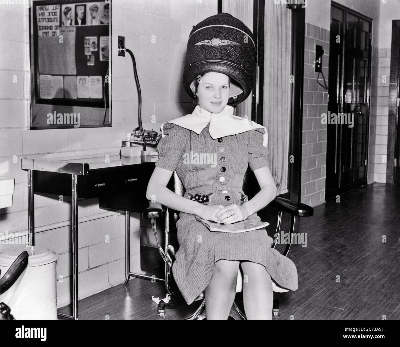 1930s SMILING WOMAN LOOKING AT CAMERA SITTING UNDER ELECTRIC HAIR DRYER IN  PROFESSIONAL BEAUTICIAN TRAINING SCHOOL - s1482 HAR001 HARS LADIES PERSONS  TEENAGE GIRL PROFESSION B&W EYE CONTACT SKILL OCCUPATION HAPPINESS SKILLS