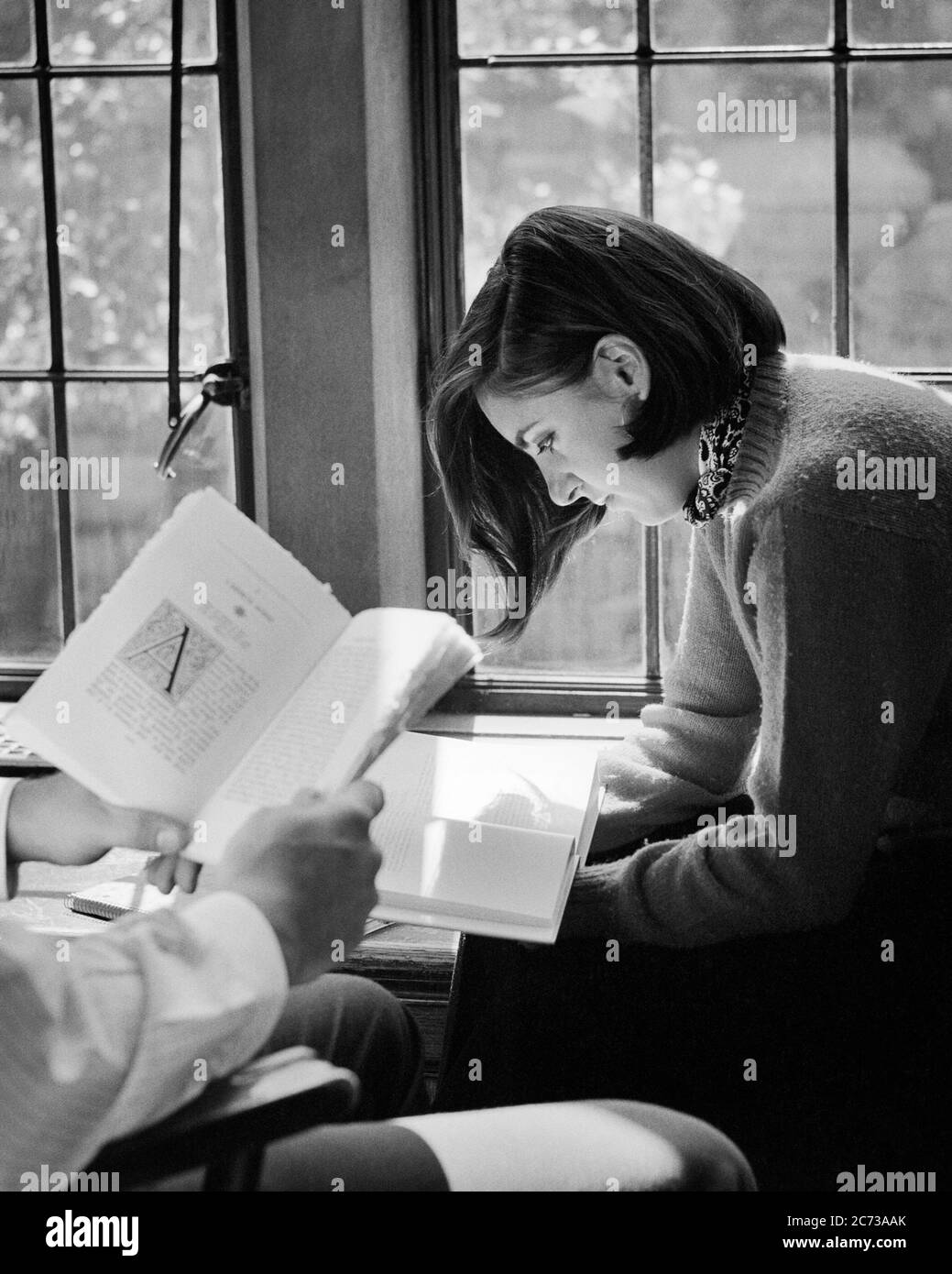 1960s 1970s FEMALE COLLEGE STUDENT BY WINDOW SUNLIGHT READING A BOOK MALE STUDENT HAND AND BOOK ONLY - s17257 HAR001 HARS INFORMATION MYSTERY LIFESTYLE FEMALES COPY SPACE HALF-LENGTH LADIES PERSONS INSPIRATION SUNLIGHT SERENITY SPIRITUALITY CONFIDENCE B&W BRUNETTE GOALS HIGH ANGLE DISCOVERY UNIVERSITIES KNOWLEDGE OPPORTUNITY HIGHER EDUCATION STYLISH TEENAGED COLLEGES COED FOCUSED GROWTH IDEAS LITERATURE YOUNG ADULT WOMAN BLACK AND WHITE CAUCASIAN ETHNICITY CONCENTRATING CONCENTRATION HANDS ONLY HAR001 OLD FASHIONED Stock Photo