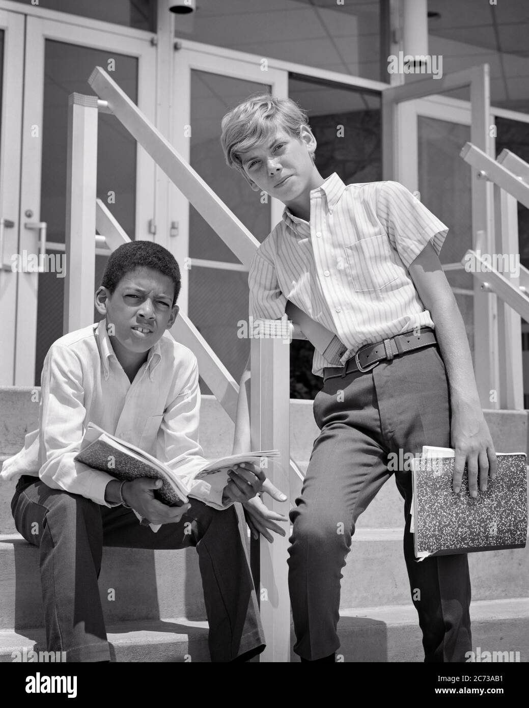 1960s TWO PRETEEN BOYS ONE CAUCASIAN ONE AFRICAN AMERICAN TOGETHER LOOKING AT CAMERA QUESTIONING ON STEPS OF SCHOOL BUILDING - s17495 HAR001 HARS EXPRESSION OLD TIME NOSTALGIA OLD FASHION 1 JUVENILE FACIAL STYLE NOTEBOOK COMMUNICATION FRIEND TEAMWORK INFORMATION LIFESTYLE SATISFACTION COPY SPACE FRIENDSHIP HALF-LENGTH PERSONS MALES TEENAGE BOY EXPRESSIONS B&W EYE CONTACT GOALS SCHOOLS AFRICAN-AMERICANS AFRICAN-AMERICAN AND KNOWLEDGE BLACK ETHNICITY HIGH SCHOOL PRETEEN HIGH SCHOOLS CONNECTION CONCEPTUAL FRIENDLY STYLISH TEENAGED GROWTH JUVENILES MIDDLE SCHOOL PRE-TEEN PRE-TEEN BOY QUESTIONING Stock Photo