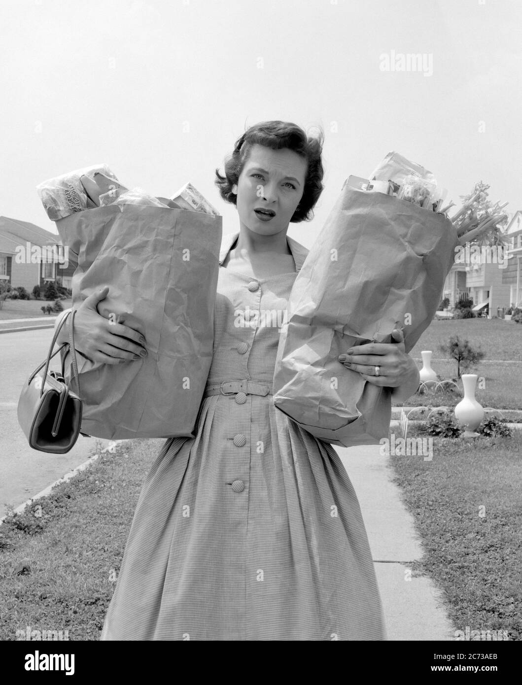 1950s WOMAN WORRIED ANXIOUS TIRED EXHAUSTED FACIAL EXPRESSION CARRYING HOLDING TWO BROWN PAPER BAGS FULL OF GROCERIES - s8671 DEB001 HARS NOSTALGIA OLD FASHION 1 ANGER FEAR COMMUNICATION YOUNG ADULT BALANCE SIGNAL WORRY CARRY BROWN LIFESTYLE ANNOYED FEMALES GROWNUP HOME LIFE COMMUNICATING COPY SPACE HALF-LENGTH LADIES PERSONS GROWN-UP HEAVY RISK CONTEMPLATING B&W SADNESS SHOPPER EYE CONTACT HOMEMAKER OVERWORKED SHOPPERS HOMEMAKERS NEIGHBORHOOD ANXIOUS DISTRESSED IRATE HOUSEWIVES PONDER PONDERING DEB001 DISPLEASURE HOSTILITY ANNOYANCE COMMUNICATE CONTEMPLATE EMOTION EMOTIONAL IRRITATED NEEDS Stock Photo
