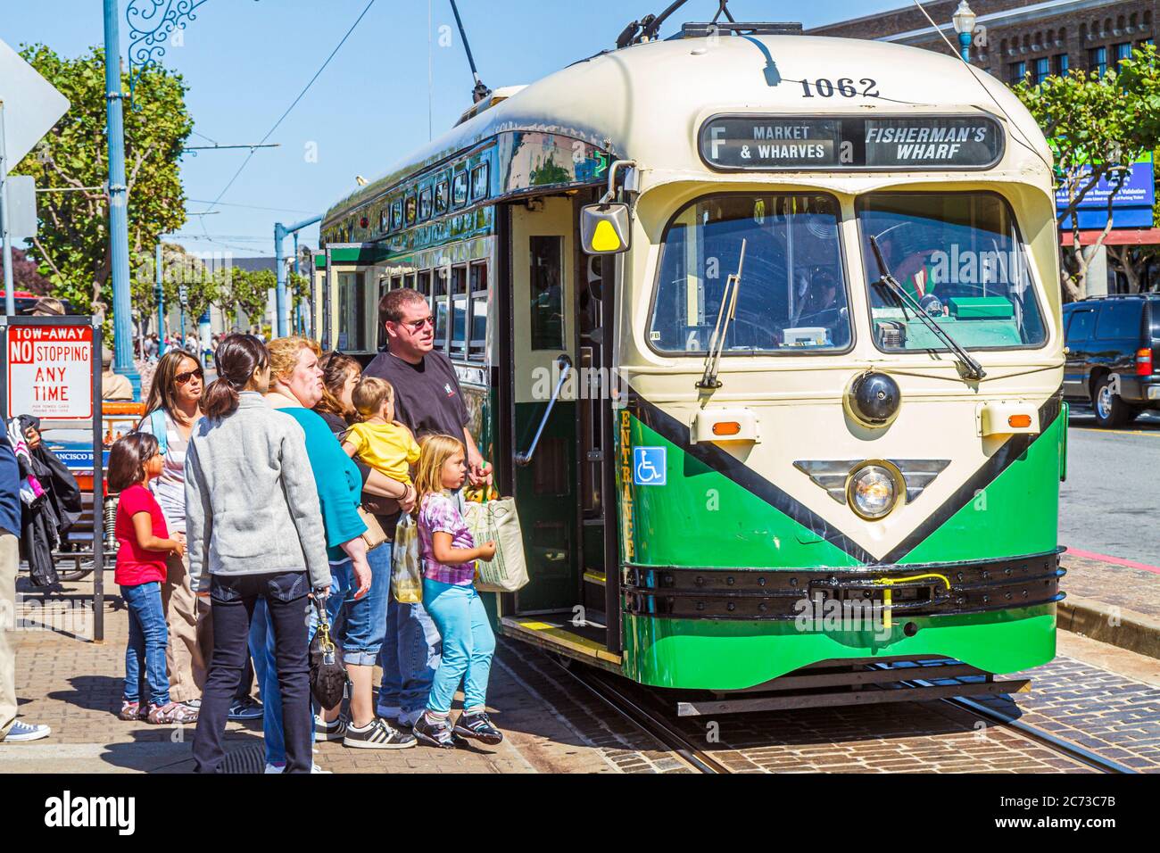 San Francisco California,The Embarcadero,electric streetcar,trolley pole,passenger rail,bus stop,boarding,woman female women,man men male,boy boys,kid Stock Photo