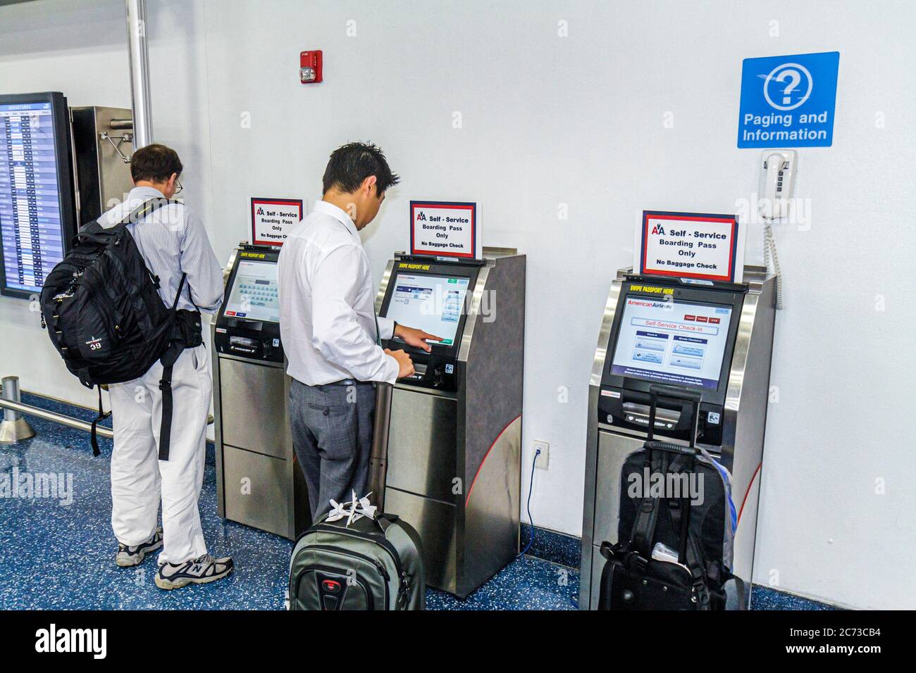 Miami Florida International Airport MIA,terminal,American Airlines,carrier,self service boarding pass,Asian man men male adult adults,luggage,suitcase Stock Photo