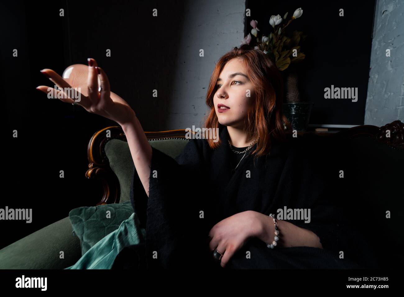 Woman in black suit holding crystal ball Stock Photo - Alamy