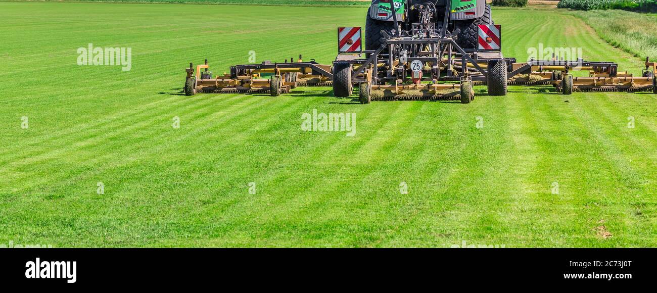 Industrial lawn mower cutting the grass in a large farm field Stock Photo