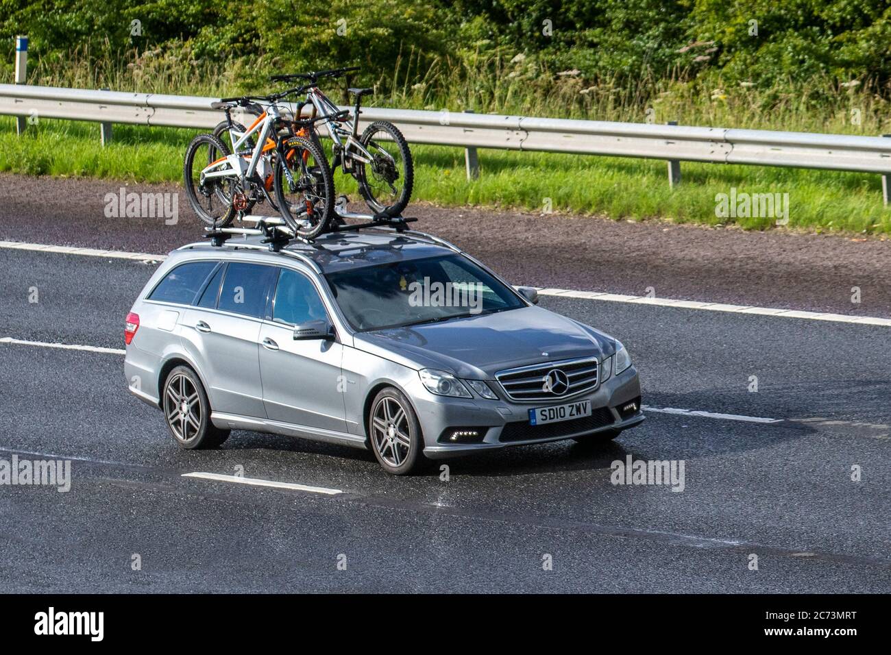 2010 silver Mercedes-Benz E220 Bluef-Cy Sport CDI A with cycle rack & bicycles; Vehicular traffic moving vehicles, cars driving vehicle on UK roads, motors, motoring on the M6 motorway highway network. Stock Photo