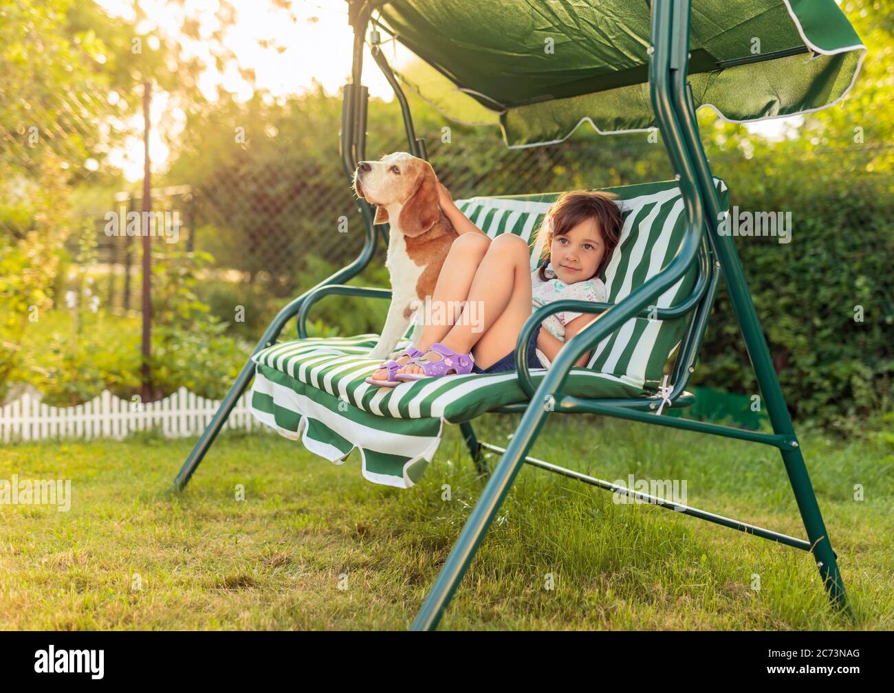 Little girl is resting on a bench with her dog. Summer evening in the ...