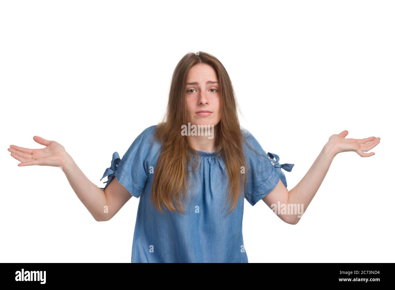 A young girl with long hair in a blue dress. Isolated on a white background, throws up his hands in doubt Stock Photo