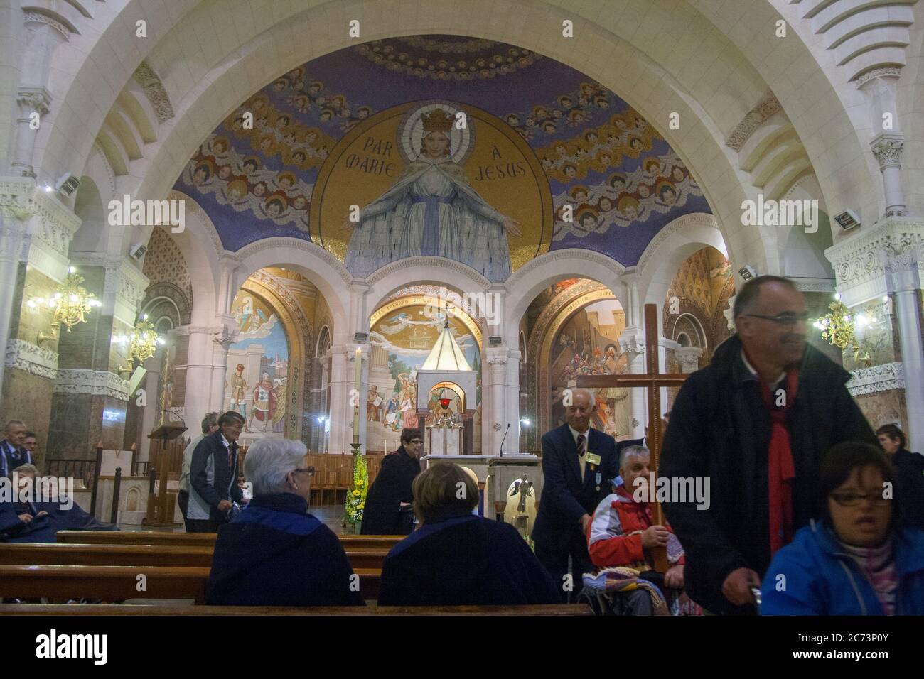 Apr 28. 2014 Lourdes France Through Mary to Jesus. Disabled people in wheelchair hope miracouolus healing. Monumental mosaic murals in Rosary Basilica Stock Photo
