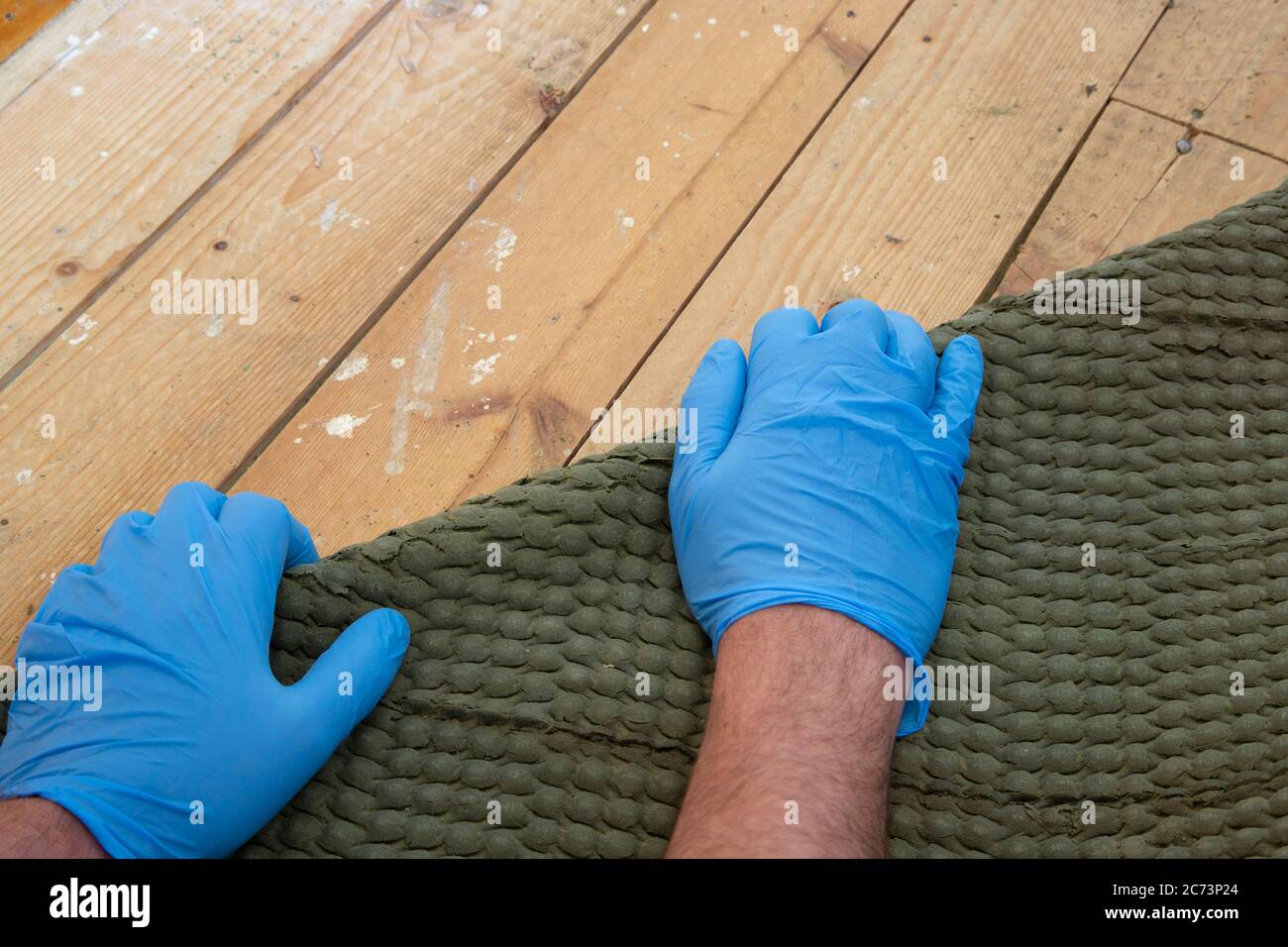 Man pulling up and removing carpet underlay from a wooden floor. Home