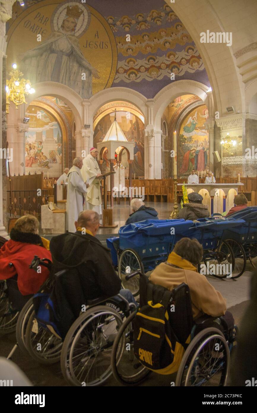 Apr 28. 2014 Lourdes France Bishop prays for the healing of sick people in wheelchairs at Rosary Basilica. Stock Photo