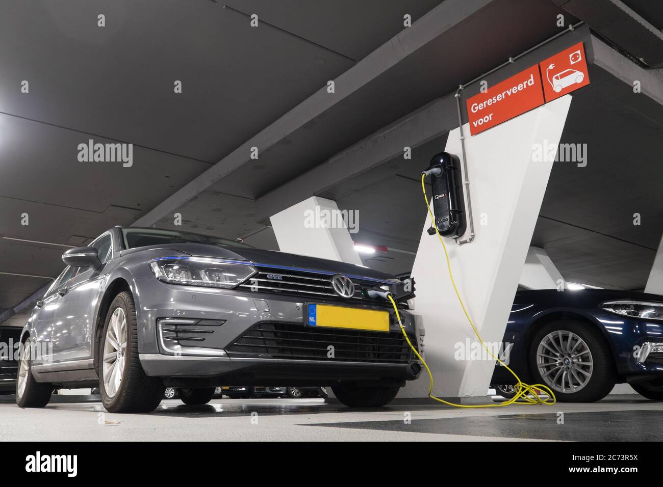 Hybrid car at charging station in underground parking with power supply