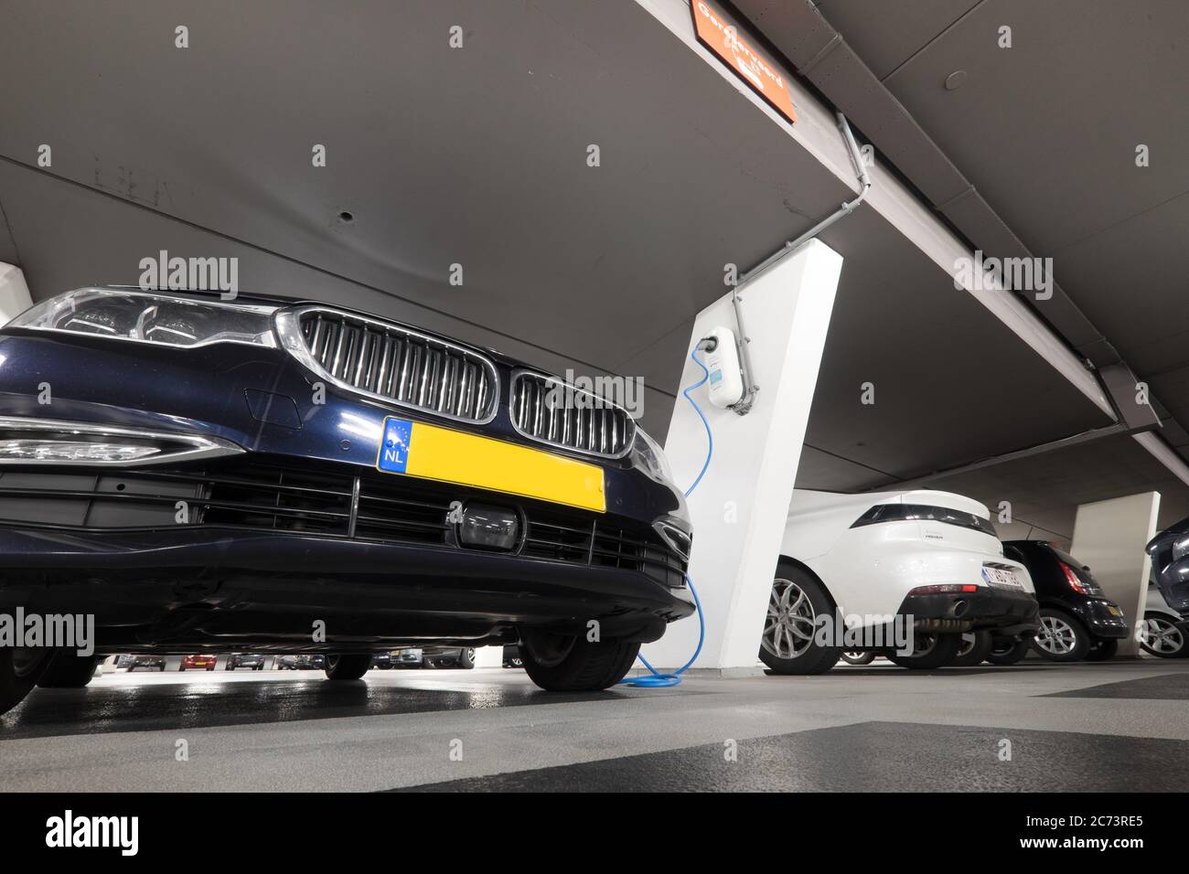 Hybrid car at charging station in underground parking with power supply