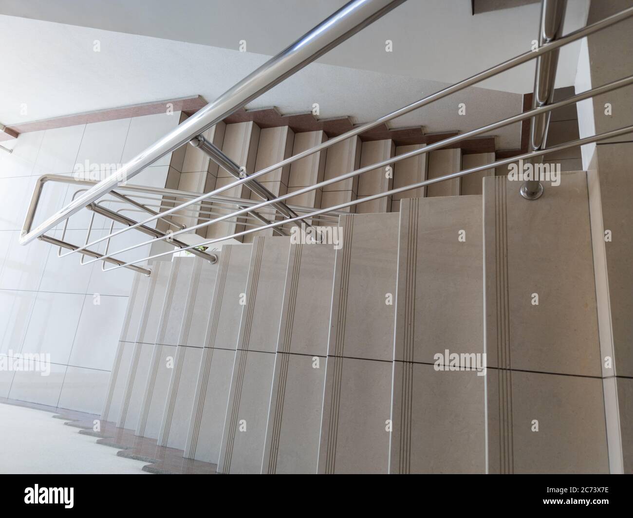 modern design of stanless steel pipes handrail and ceramic tiles staircase in abstract public building Stock Photo