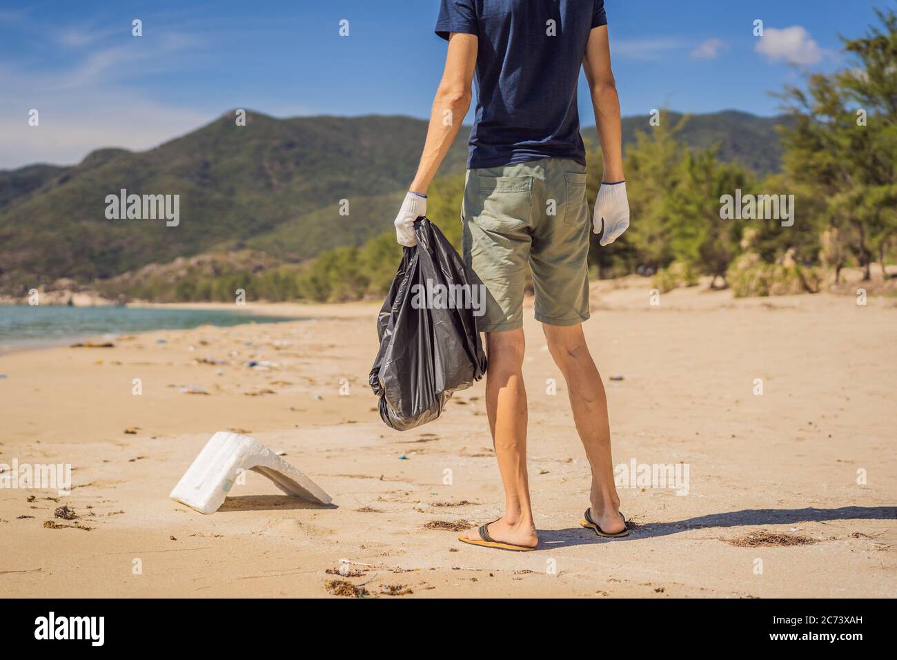 Man in gloves pick up plastic bags that pollute sea. Problem of spilled