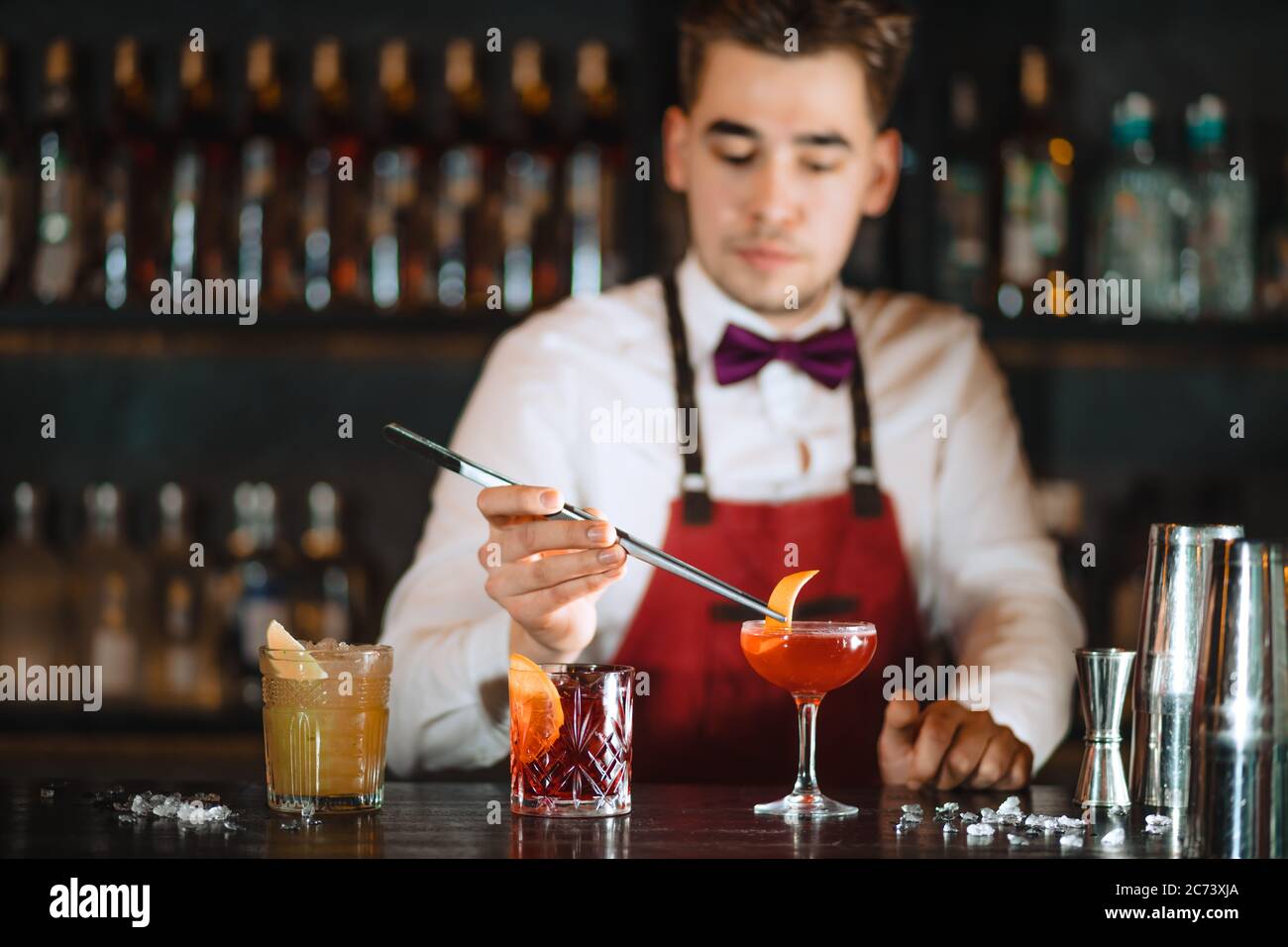Bartender adding to cocktail in elegant glass one orange zest with