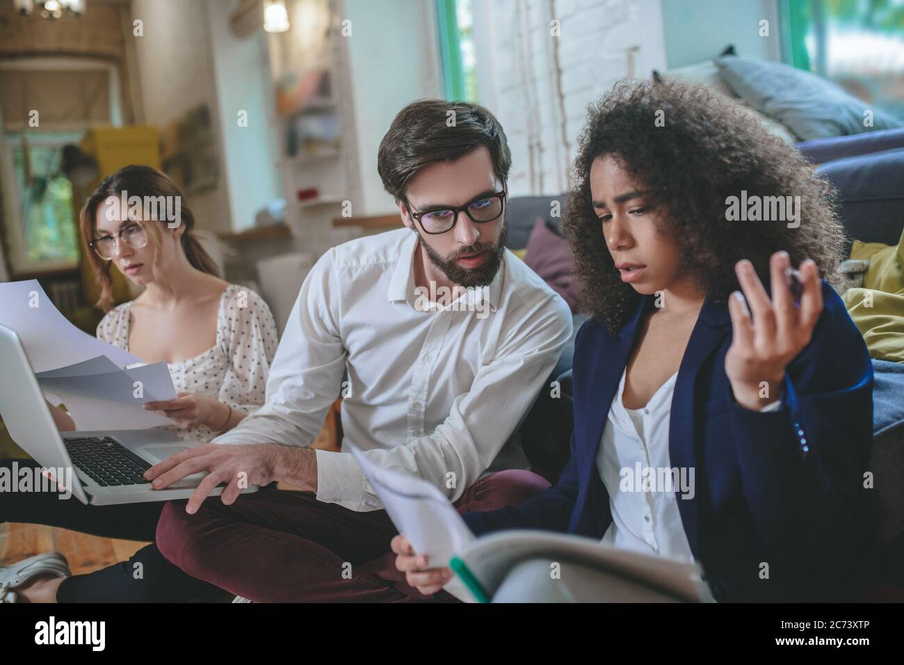 Three serious young friends working with papers at home Stock Photo