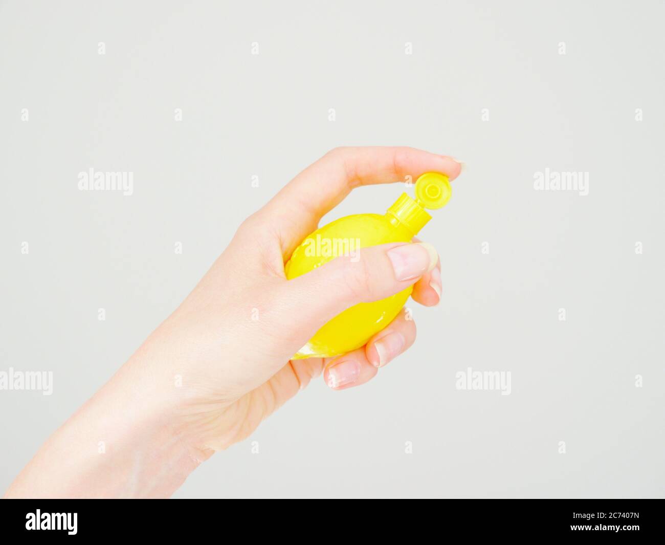 A female hand with natural nails holds a lemon squeezy Stock Photo