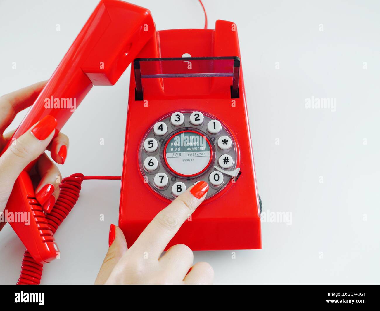 Female hands with red manicured nails make a telephone call, dialling the number 9 Stock Photo