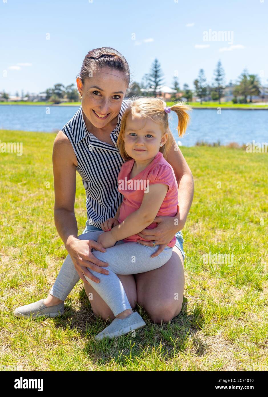 Positive portrait of mother and daughter having fun together by the lake. Cute little girl with mum in the park. Love, Family time, motherhood, childh Stock Photo