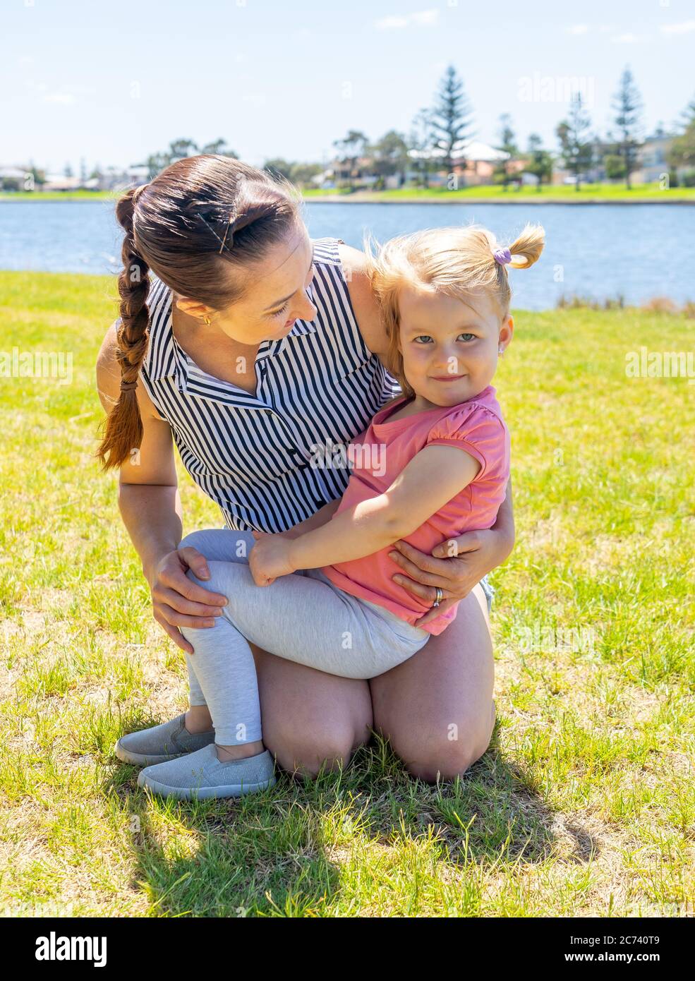 Positive portrait of mother and daughter having fun together by the lake. Cute little girl with mum in the park. Love, Family time, motherhood, childh Stock Photo
