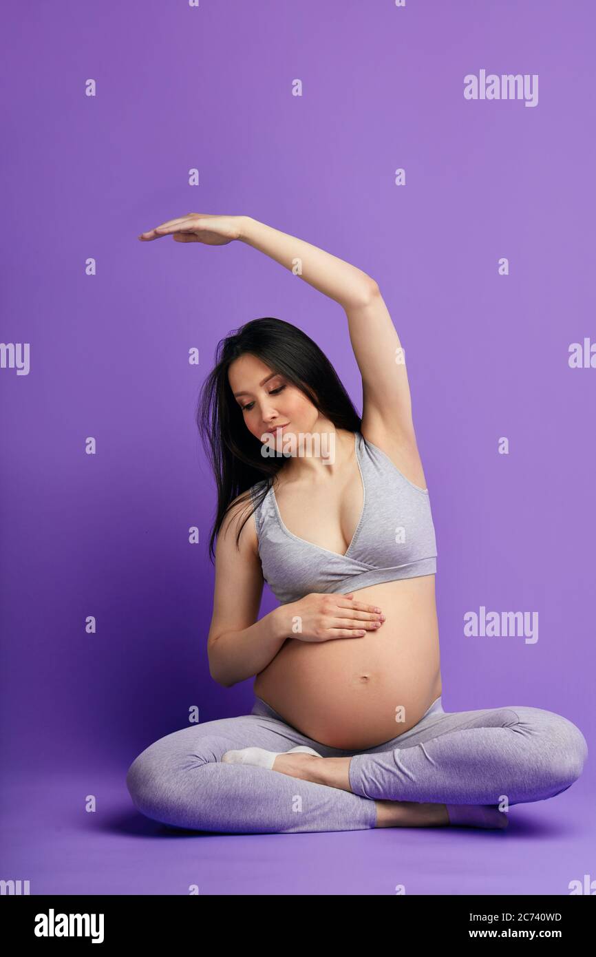 Care about unborn child. Happy pregnant woman practicing prenatal yoga classes on third trimester preparing her body to natural childbirth Stock Photo