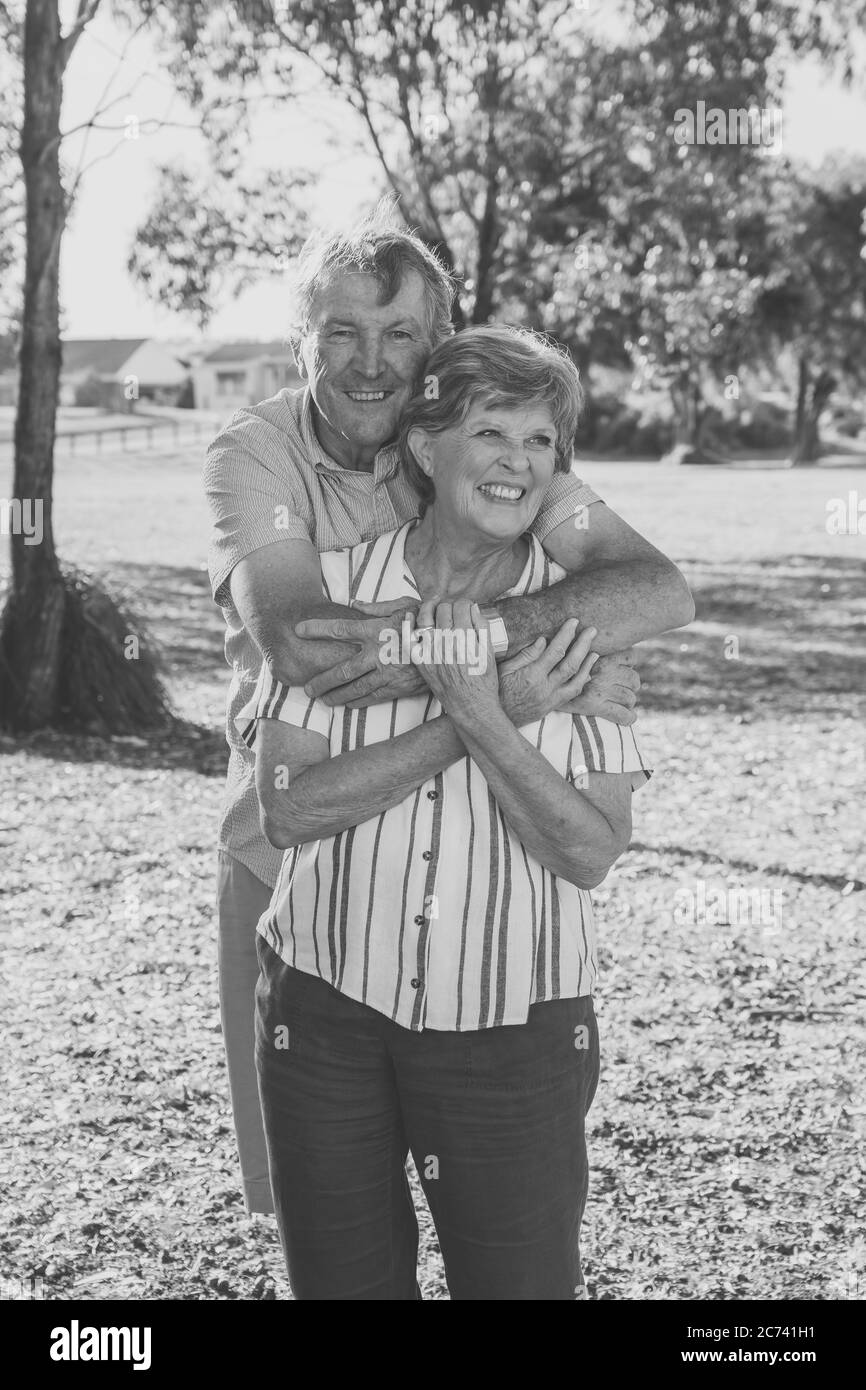 Portrait of caucasian senior couple in their 70s embracing showing love and affection in the park. Aging together, love, retirement lifestyle and back Stock Photo