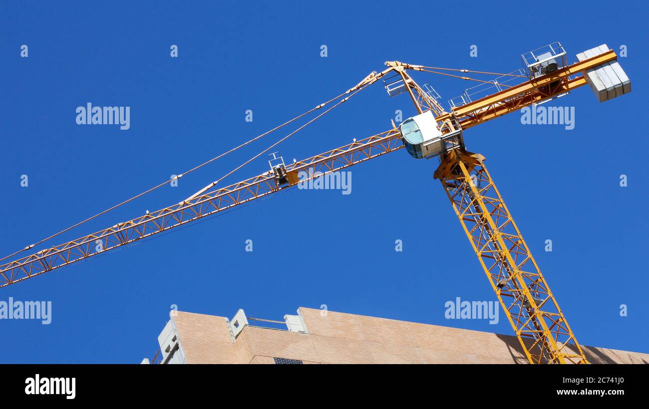 Construction crane on a background of blue sky. The construction of new homes. The concept of resuming construction sites. New apartments. Stock Photo