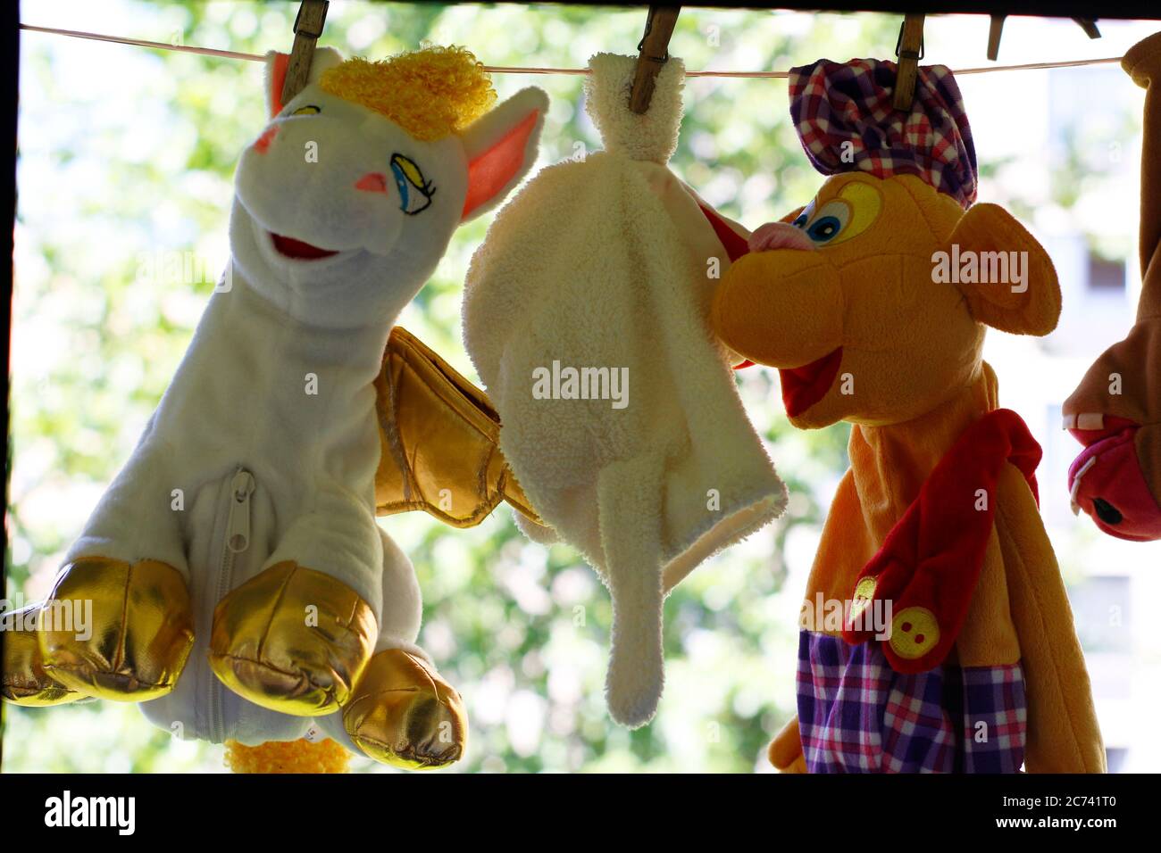 Children's toys are dried on clothespins. Soft toys hang on a clothesline, toys are fixed with clothespins. Stock Photo