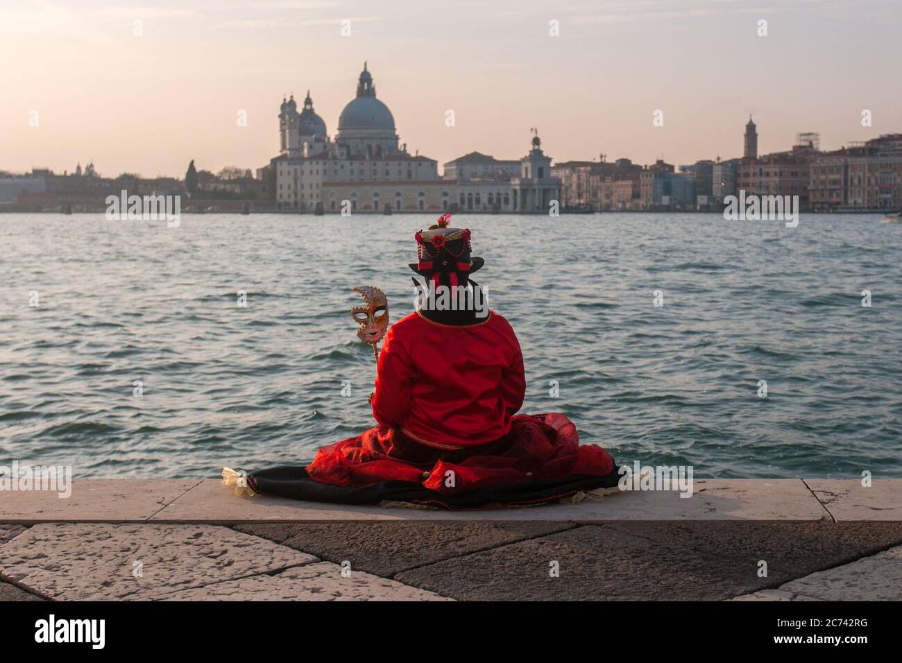 A red mask is sitting in front of the San Marco basin during Venice Carnival Stock Photo