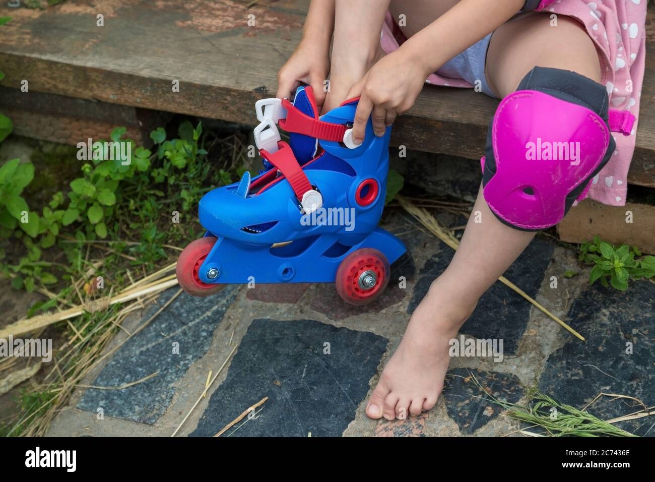 A little girl puts on roller skates sitting on the steps of her country  house Stock Photo - Alamy