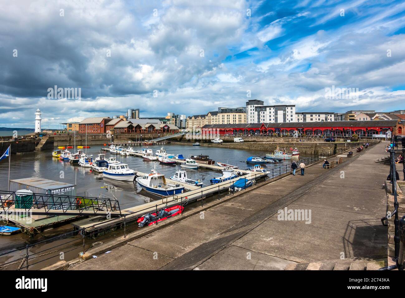 Newhaven Habour at the west end of Western Harbour Leith Docks Edinburgh Scotland with lighthouse at the harbour entrance and boats moored at low tide Stock Photo