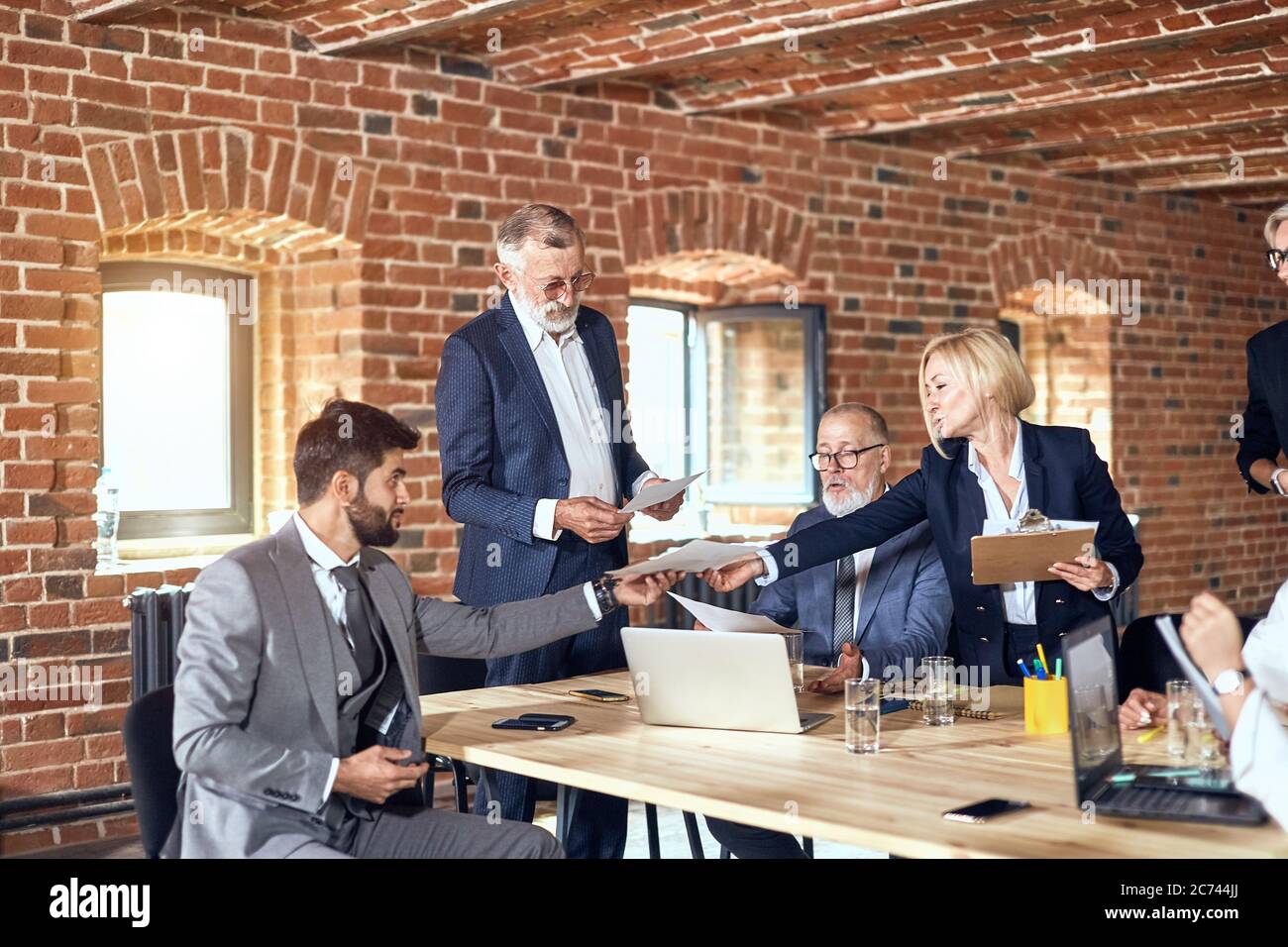 Group of businessmen in office made brick walls discuss project. Four ...