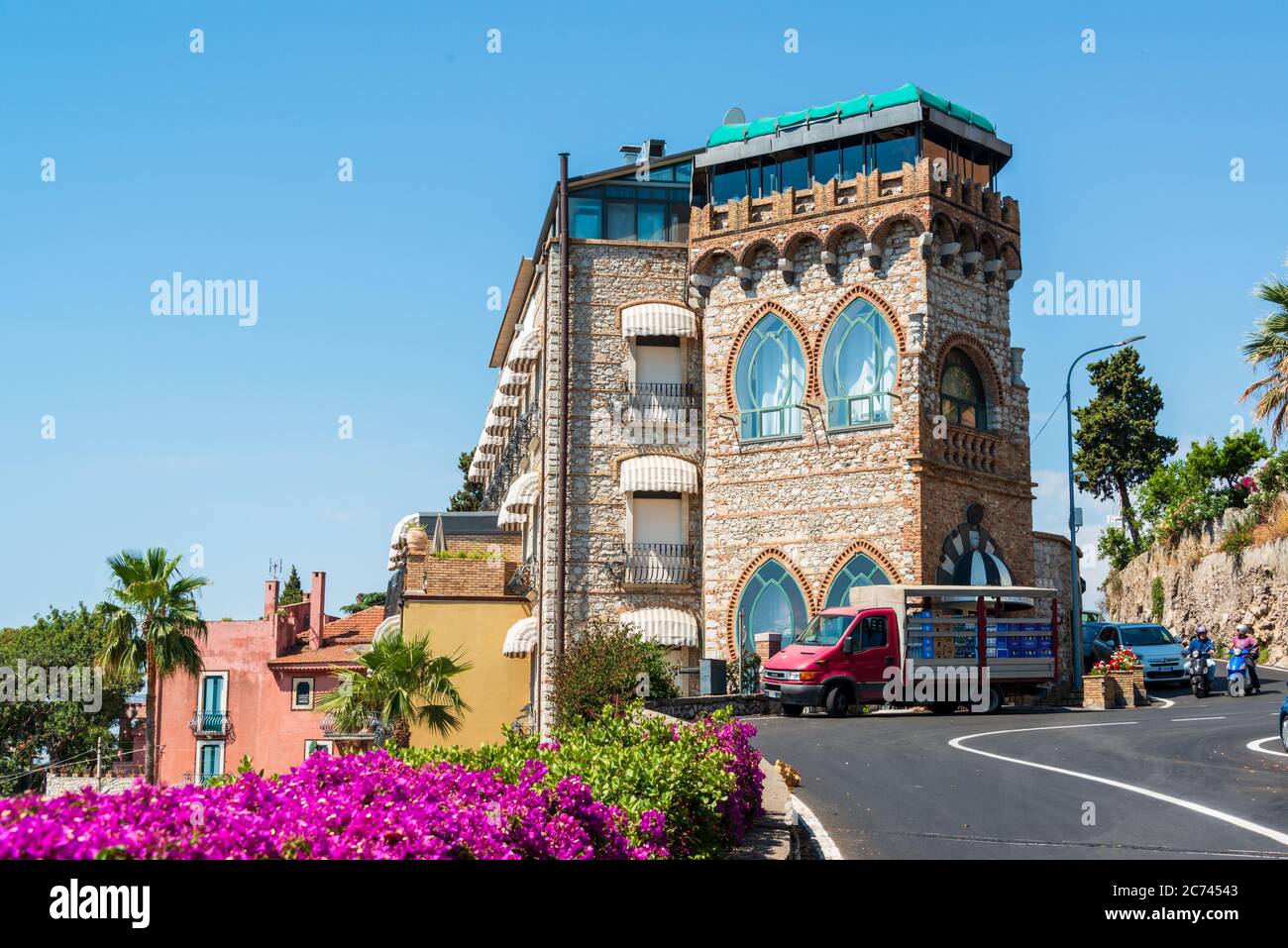 In Serpentinen führt die Straße von der Küste hoch nach Taormina, umsäumt von bunten Pflanzen und vorbei an prächtigen Hotelpalästen Stock Photo