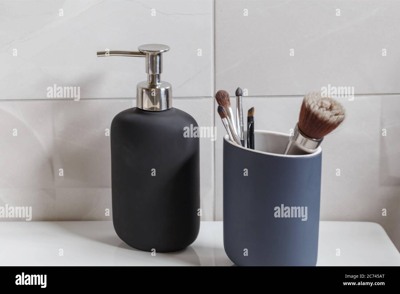 Bathroom interior with liquid soap bottle and makeup brushes closeup