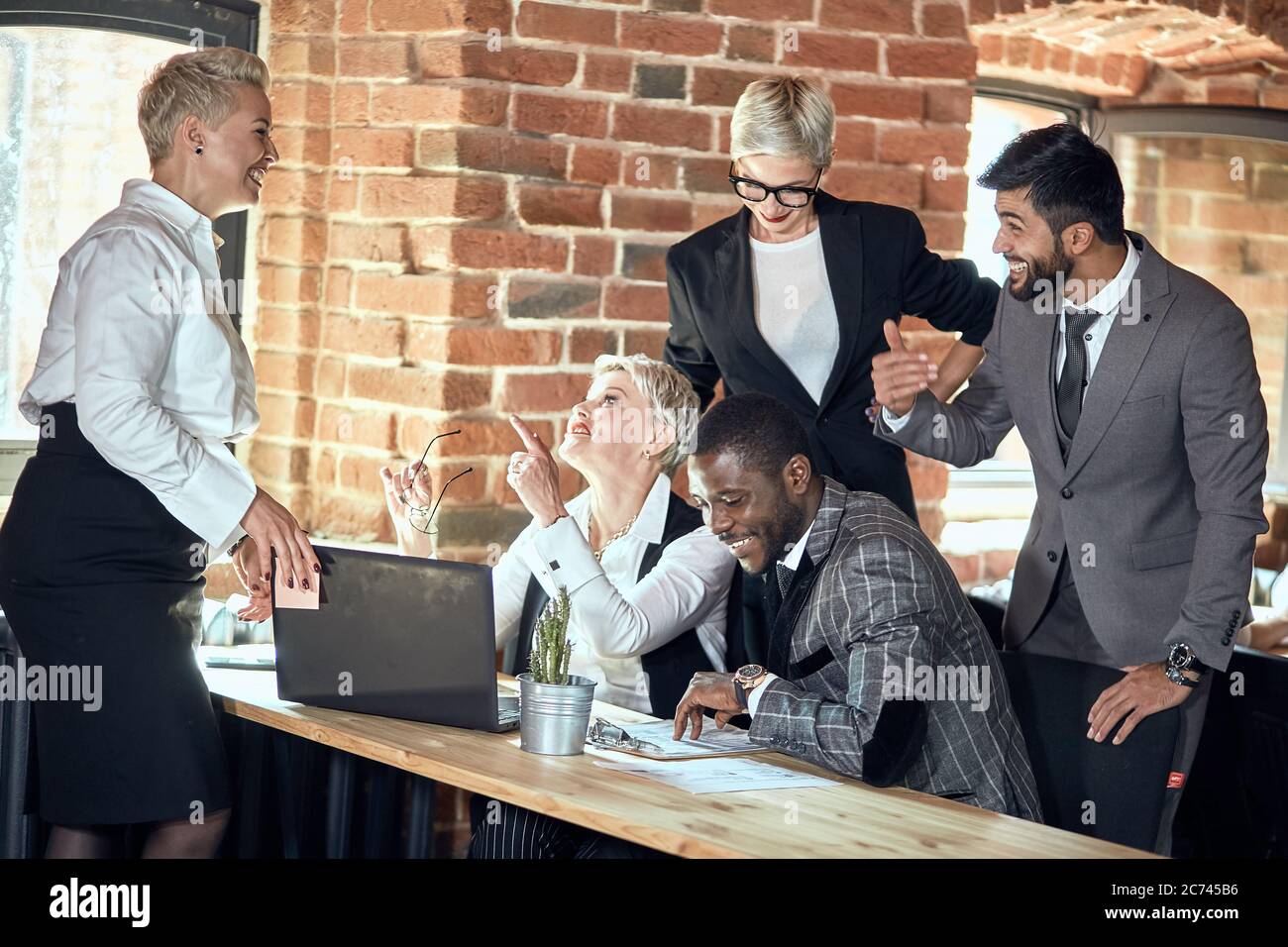 Five businessmen wear different suits discuss task at table in office ...