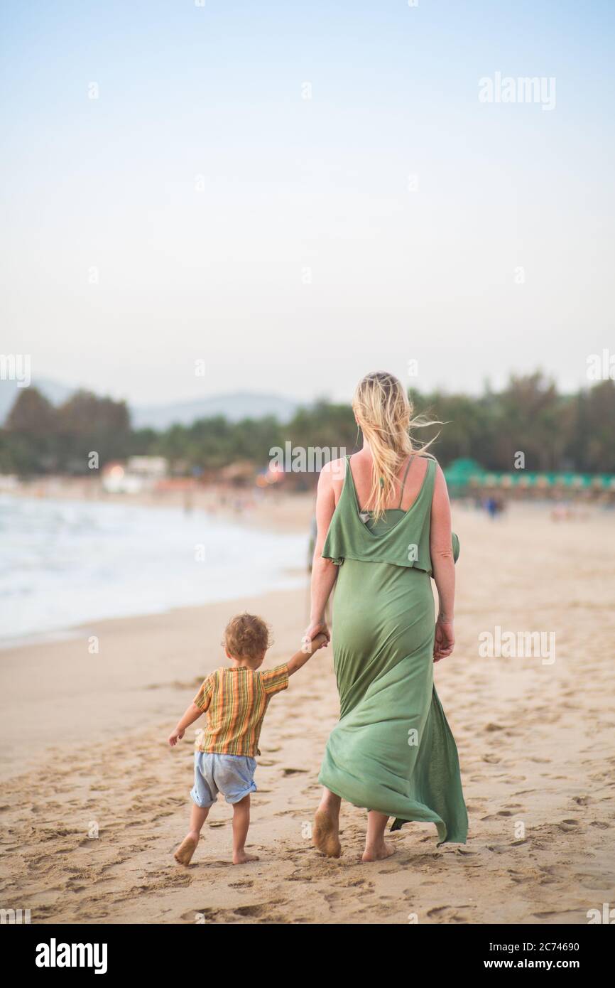 A mother walking with their child at sunset in a tropical location by the beach Stock Photo
