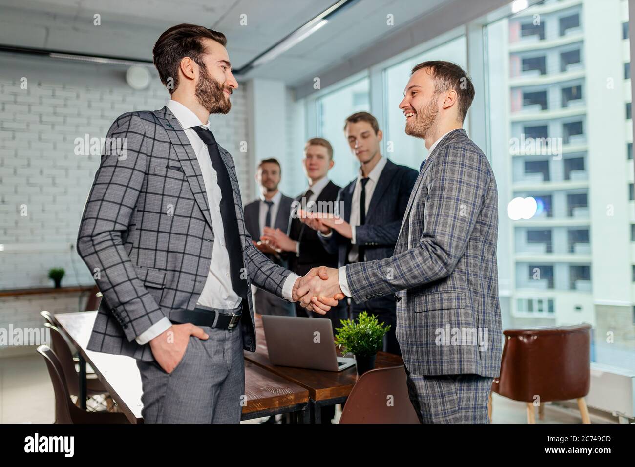 personable goodlooking business partners in grey suits shake hands to each other, after