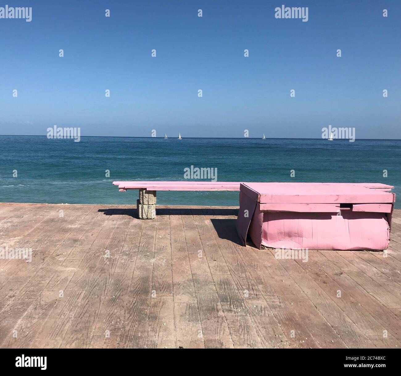 Pink bench on the beach in the morning blue sky background. Stock Photo