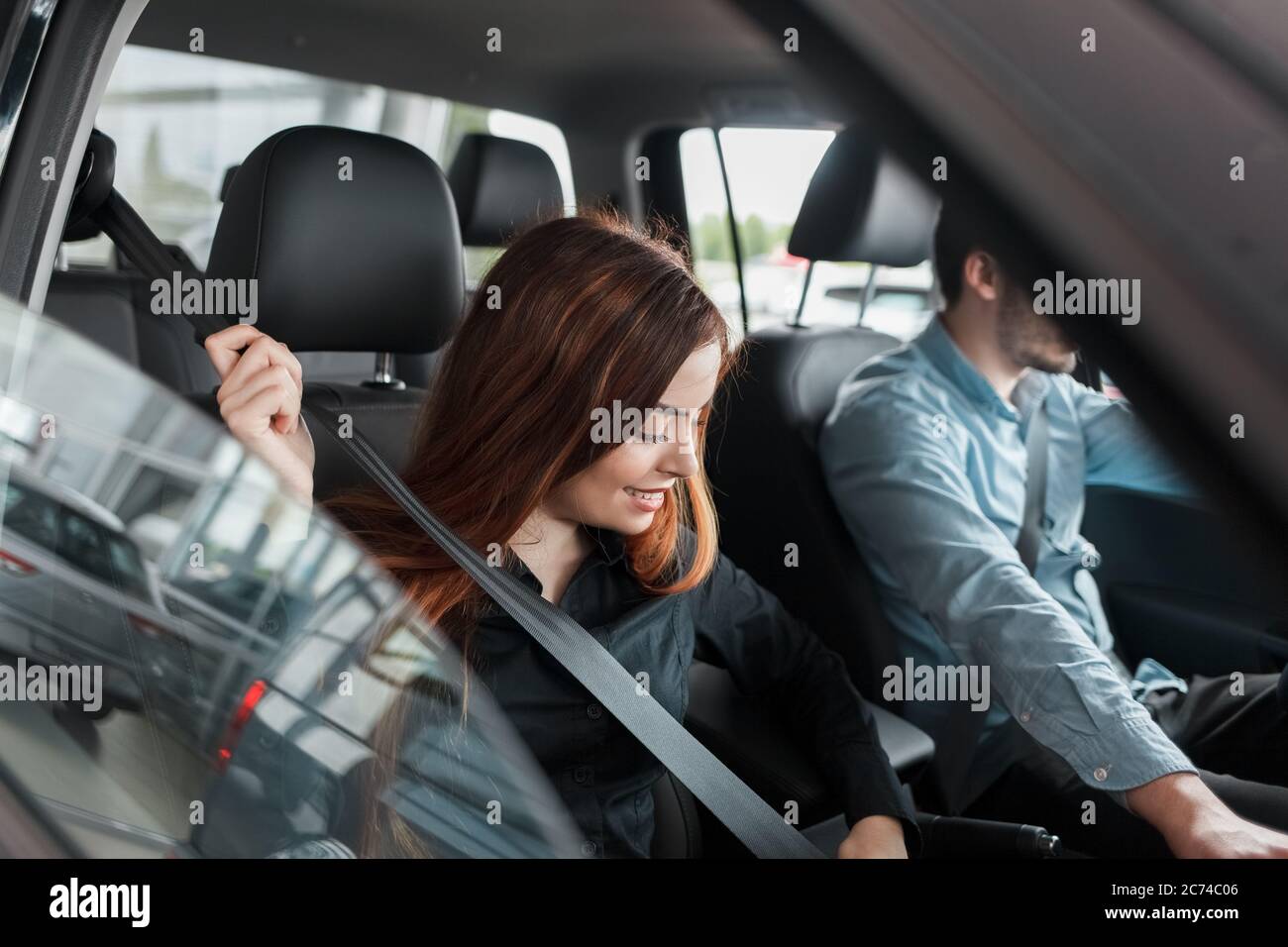 Woman fastens her seat belt before starting a test drive at a car dealership Stock Photo