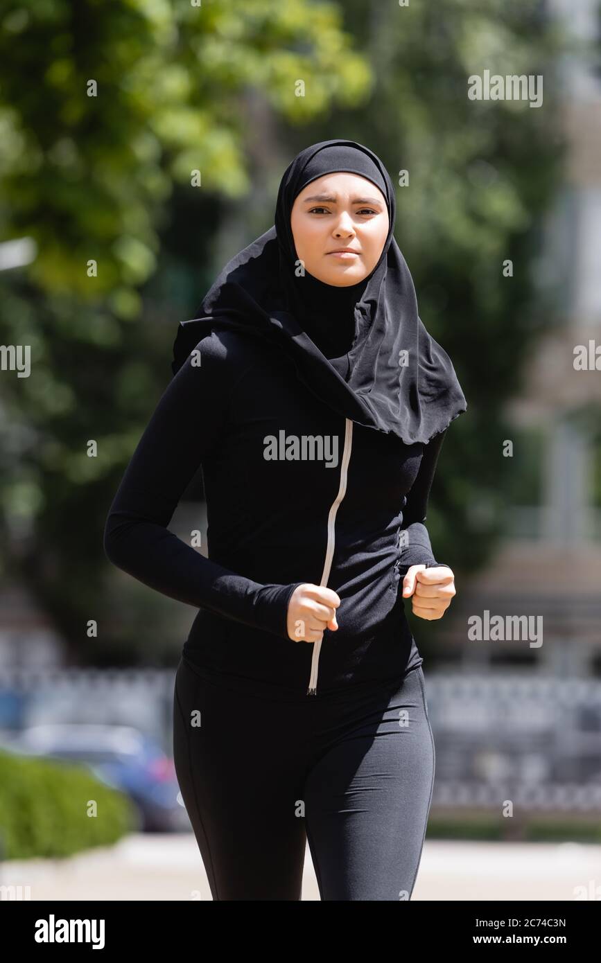 young arabian girl in hijab and sportswear jogging outside Stock Photo