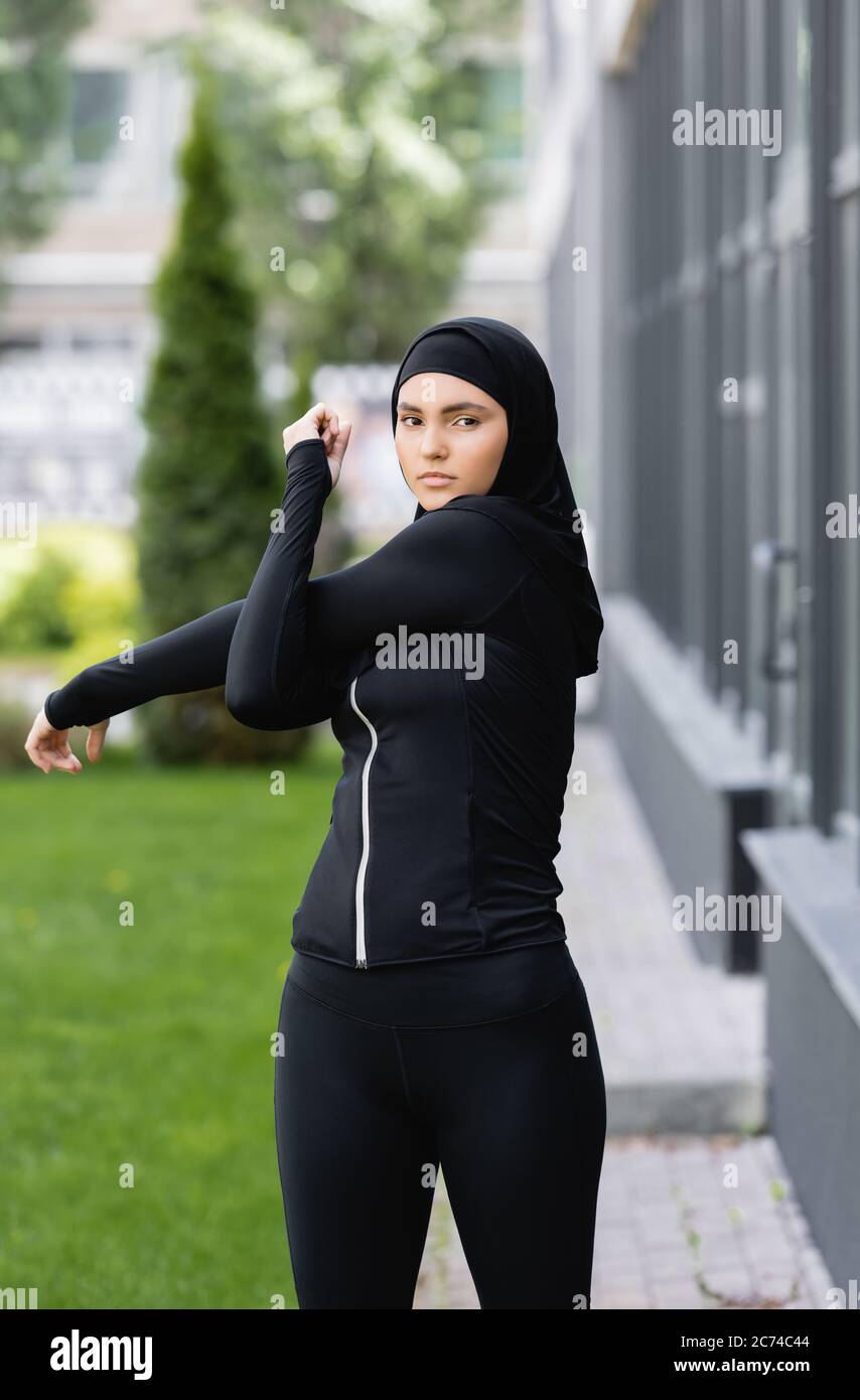 arabian girl in hijab and sportswear working out near building and green  grass Stock Photo - Alamy
