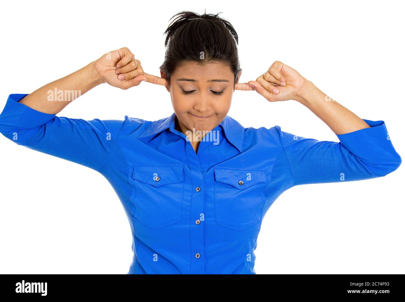 Portrait of a young unhappy stressed woman covering closed ears looking down annoyed by loud noise Stock Photo