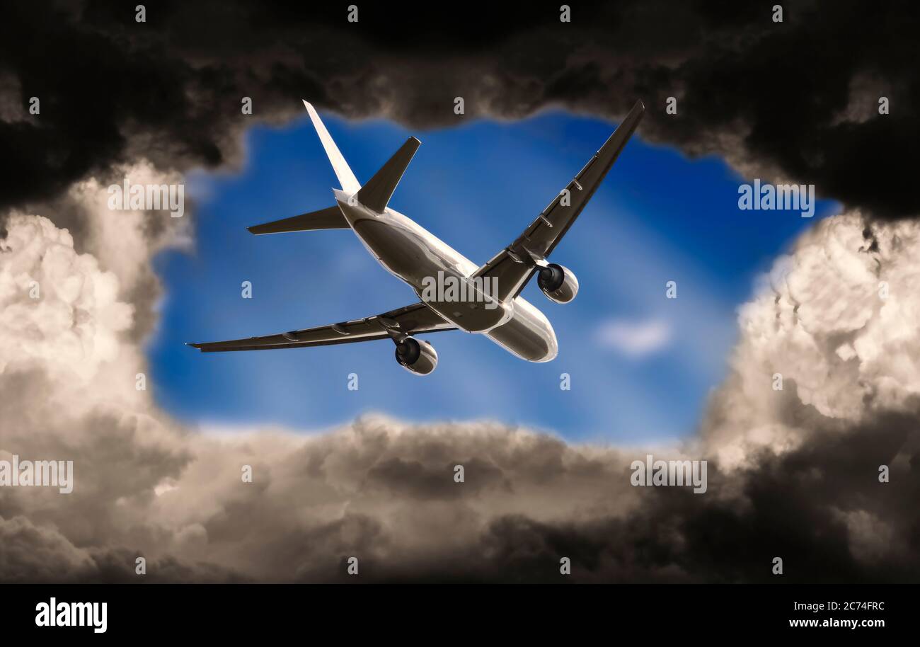 Airplane breaks through dark clouds into a blue sky Stock Photo