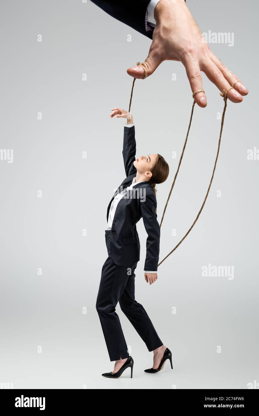 cropped view of puppeteer holding businesswoman marionette on strings  isolated on grey Stock Photo - Alamy