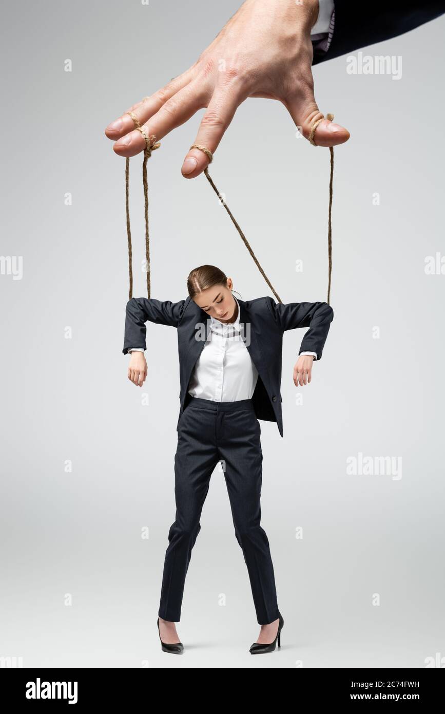 cropped view of puppeteer holding businesswoman marionette on strings  isolated on grey Stock Photo - Alamy